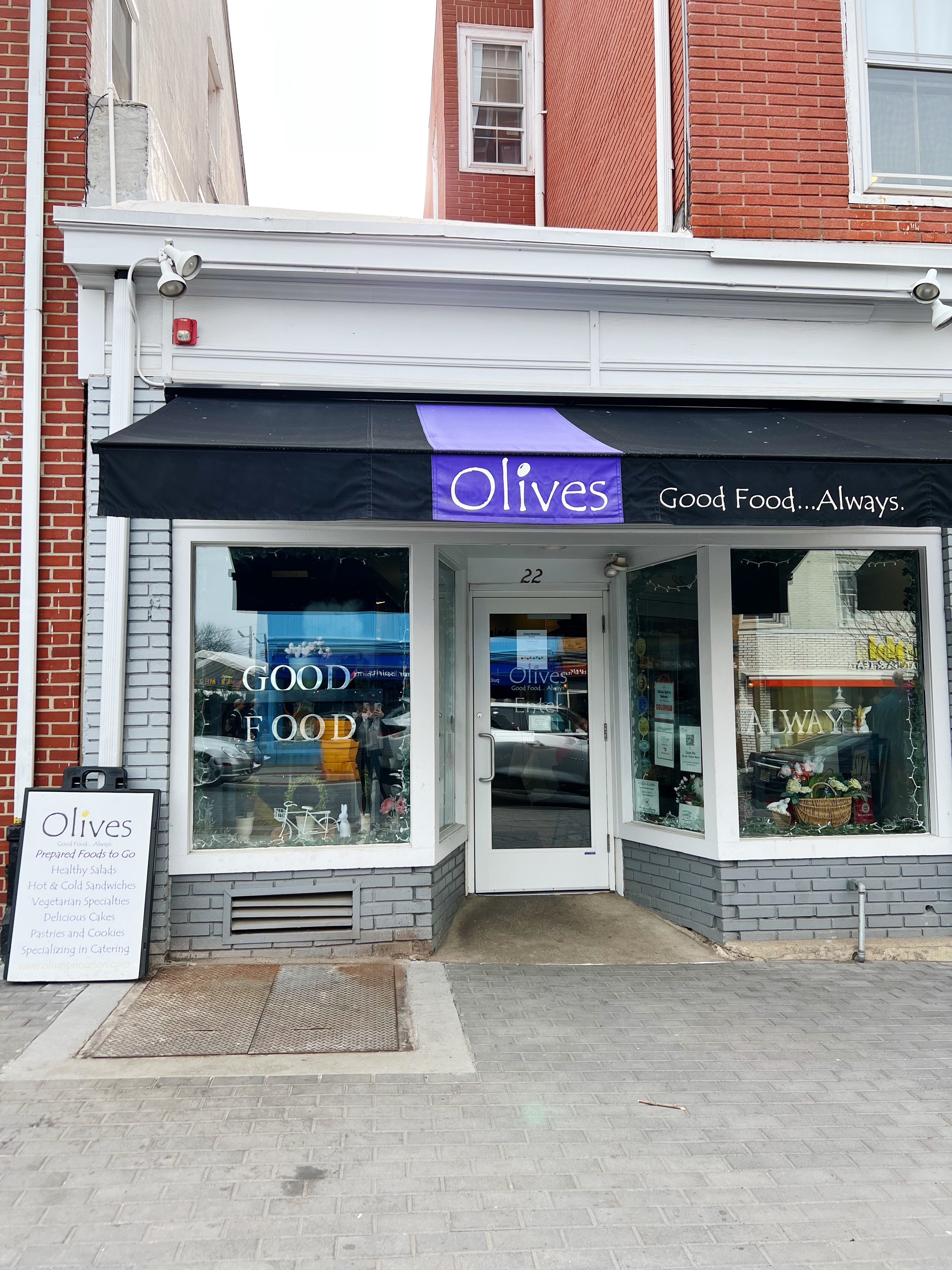 Exterior of Olives, white building with black and purple "Olives" awning