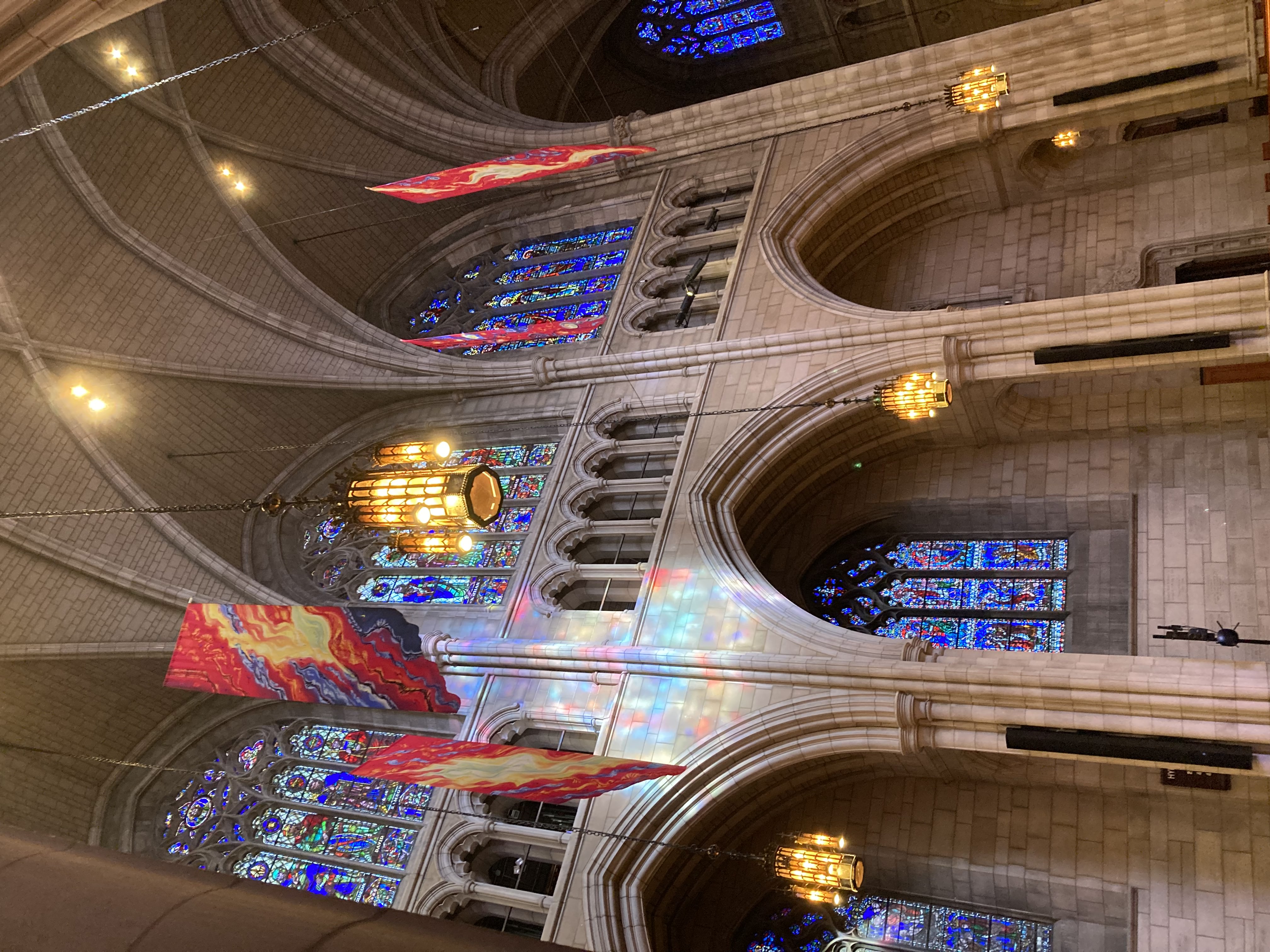 The inside of the chapel, with stained glass windows, colorful flags, lights. 