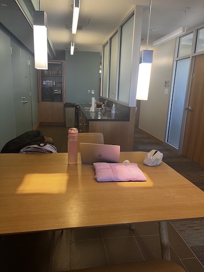 A laptop, water bottle, and pencil pouch on a wooden table