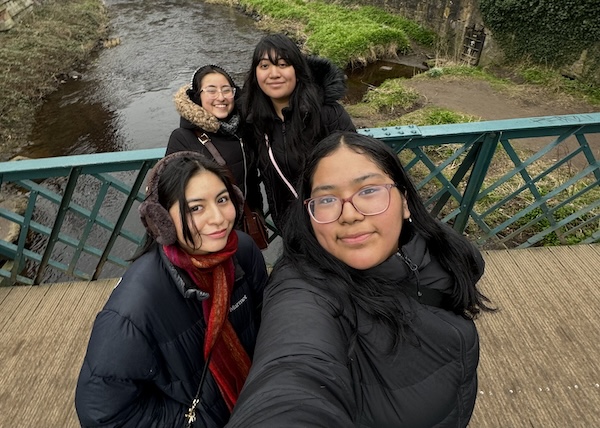 Four people smiling on a bridge. 