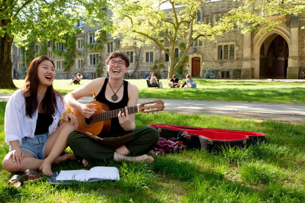 Students playing guitar on the lawn